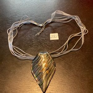 Grey glass pendant on grey ribbon necklace.